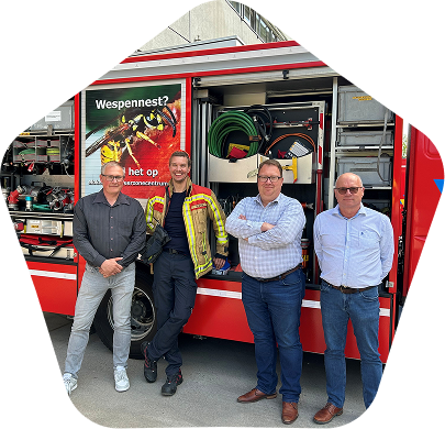 Een team van Orange Belgium en brandweerlieden poseren voor een vrachtwagen.